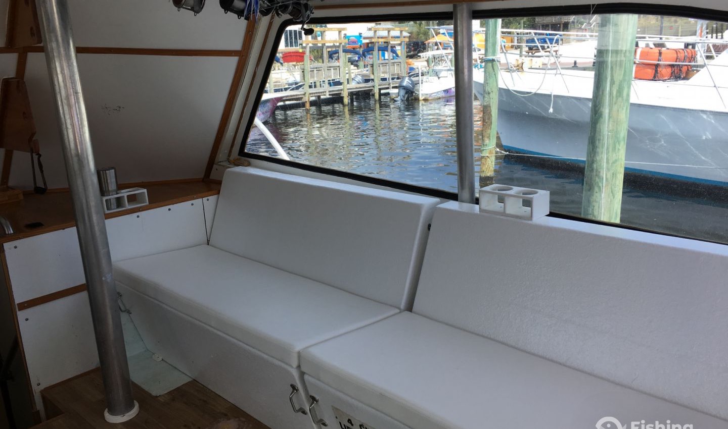 Inside the air-conditioned cabin: long white bench seating, big windows, and rod storage overhead